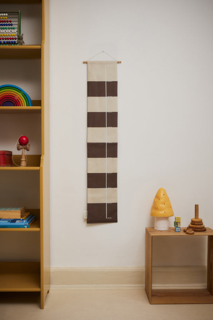Brown striped growth chart for children hanging on a wall