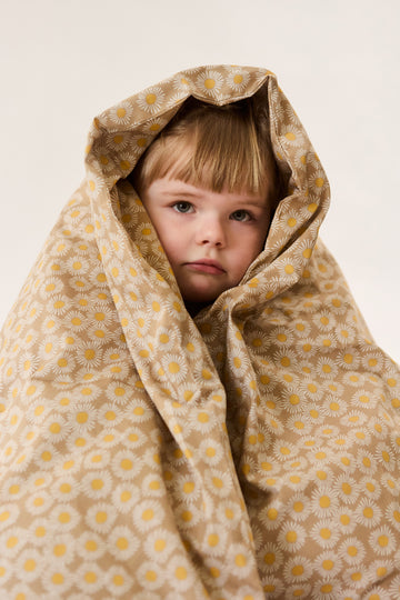 Girl wrapped in children's bedding with camel daisy print