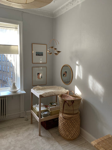 Baby mobile with cotton nightingales and wooden hanger over a changing table