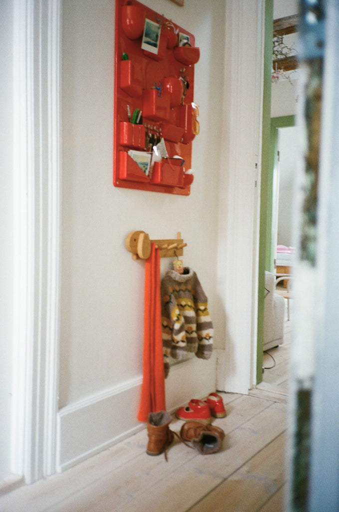 A wooden coat rack shaped like a dog hanging below a red organizer.