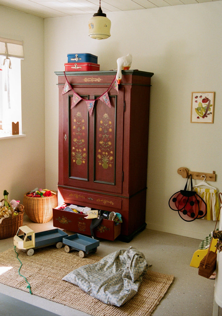 Children's room with wooden wardrobe, toys, and a window.