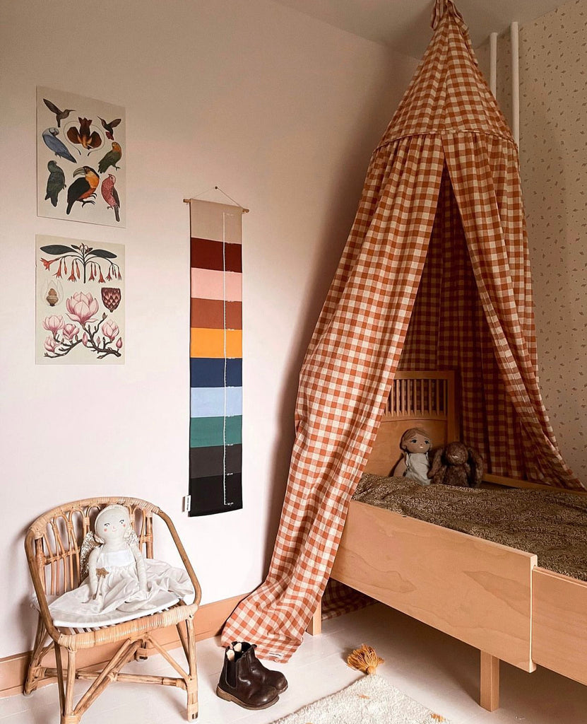 Colorful striped growth chart for children besides a bed with a canopy